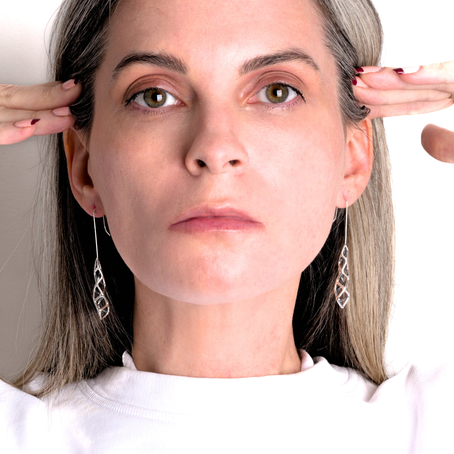 Solid sterling silver geometric lattice drop earrings are styled in this photo showing the symmetric and asymmetric properties of the dimensional designs.
