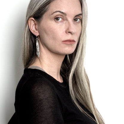 Model in a black designer top wears sculptural solid .925 sterling silver dangle earrings with angular latticework detail.