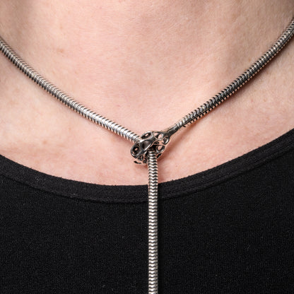 Detail of a sterling silver lariat necklace with latticework cufflet closure worn close to the neck. The long snake chain lariat drapes comfortably down the body. 