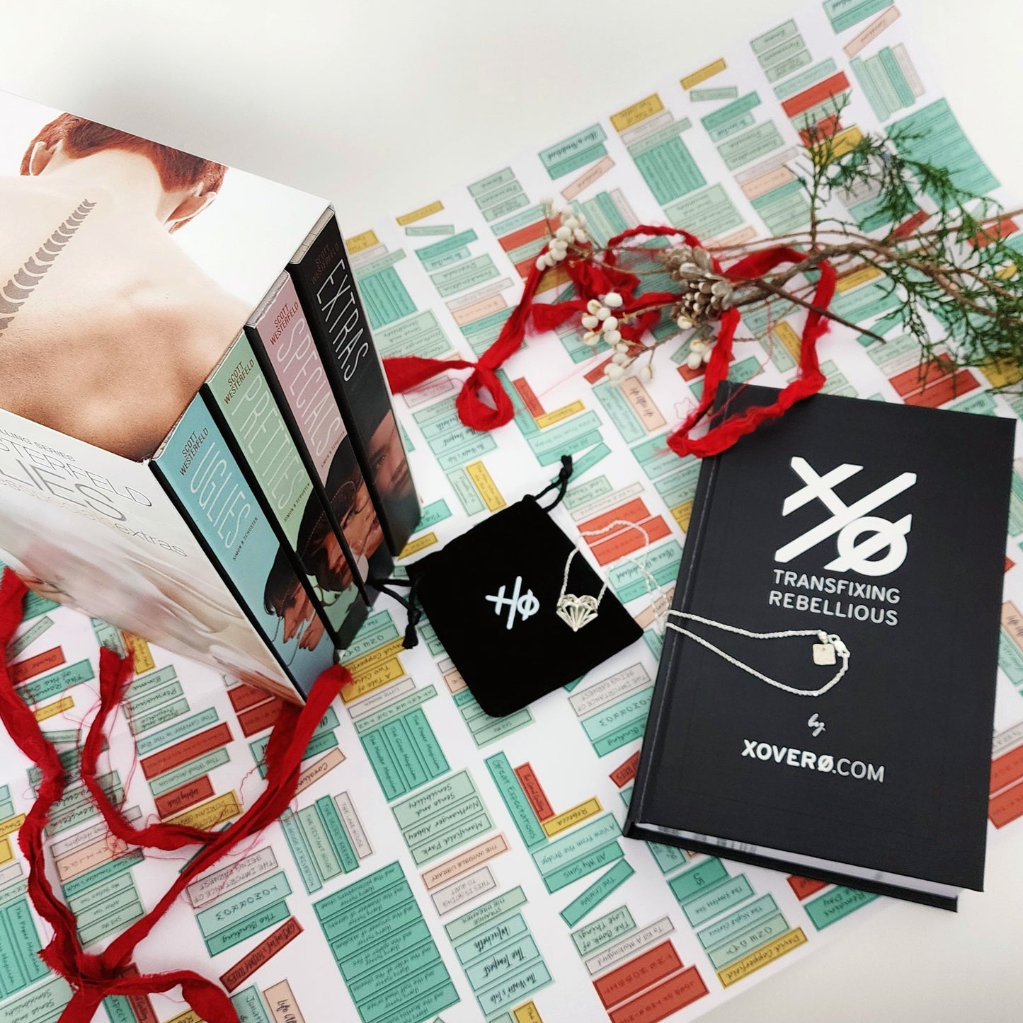 Xover0 custom Book Safe displayed alongside the Uglies 4-book series box set, with the Geoheart Pendant necklace resting on top of its black velvet pouch.