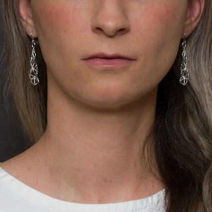 Sterling silver latticework earrings with angular geometric detail modeled by a woman. 