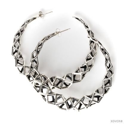 A pair of geometric lattice hoop earrings in solid sterling silver. These sculptural earrings are contrast oxidized for added impact. They are backed with matching .925 hand soldered posts. 