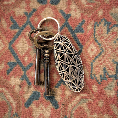 Sculptural sterling silver keychain featuring Art Deco-inspired lattice design secures antique keys. 