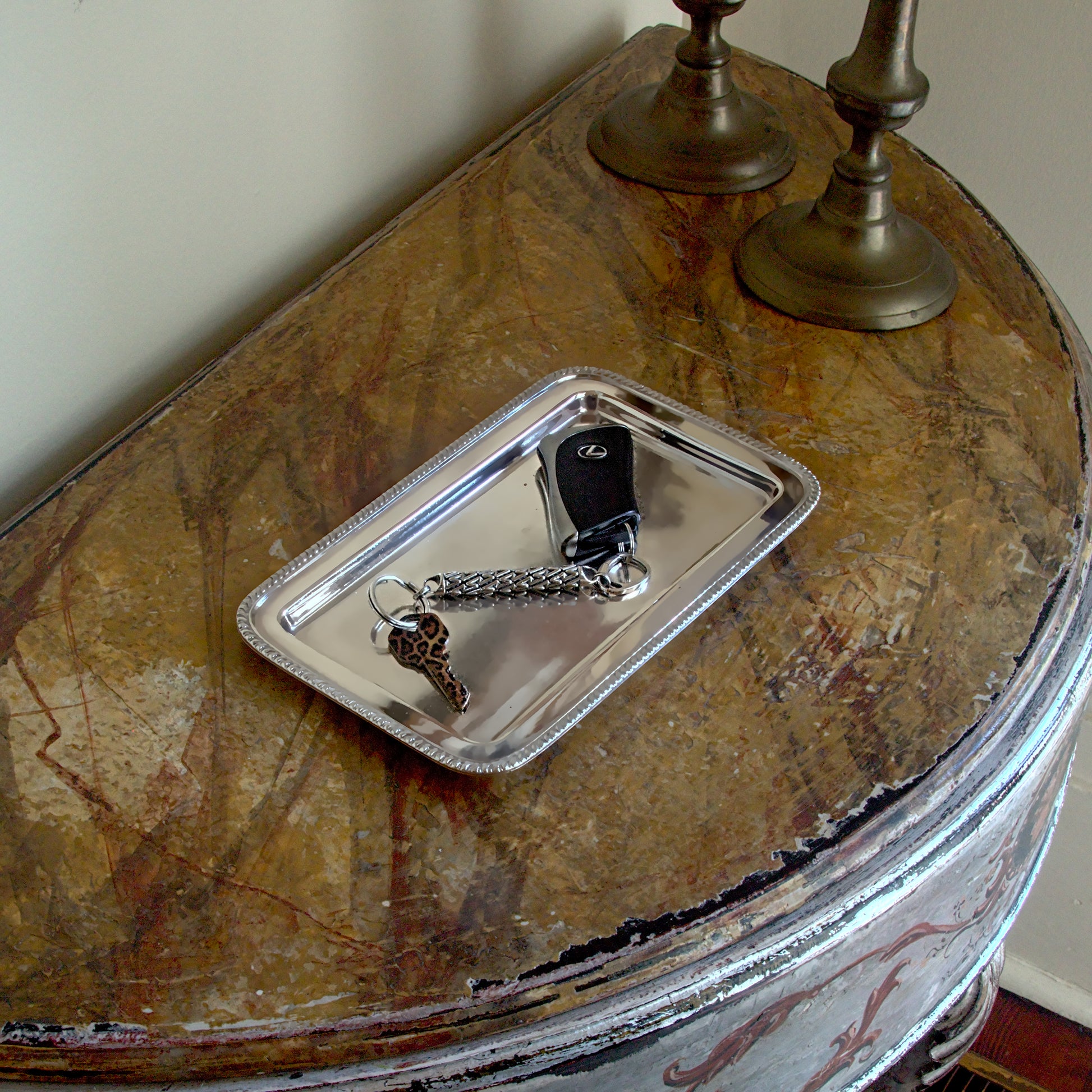 Sterling silver designer keychain with precise, detailed craftsmanship and architectural influences rests on a console in a richly decorated, luxurious interior.