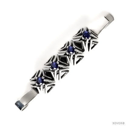 An heirloom sterling silver bobby pin with four hand-set sapphires in a geometric latticework of pointed spikes.
