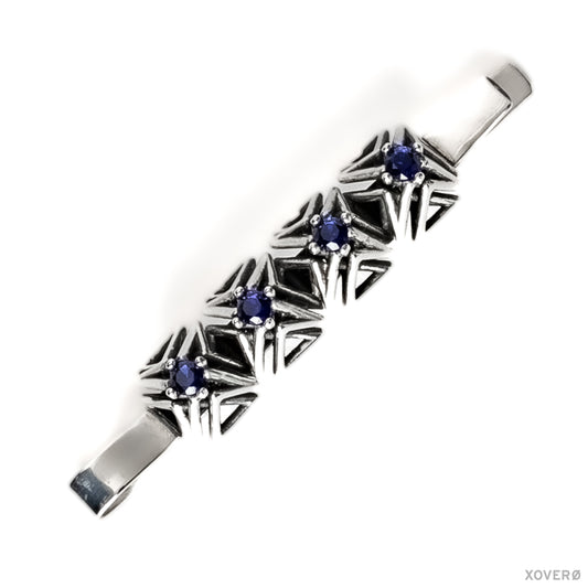 An heirloom sterling silver bobby pin with four hand-set sapphires in a geometric latticework of pointed spikes.