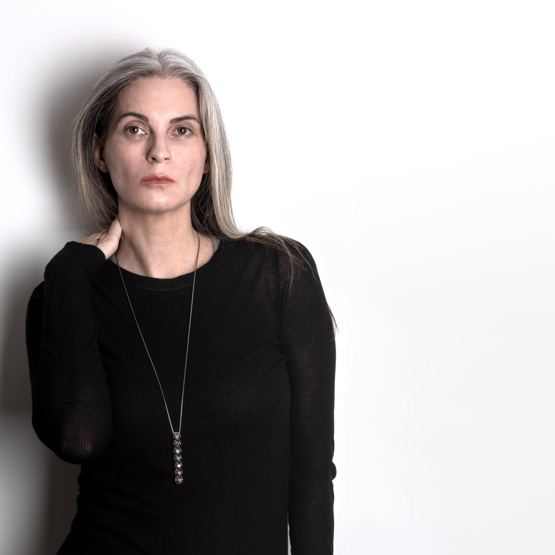 Sleek silver bar pendant with hand set colored gemstones worn with layered designer tops. A long adjustable chain secures the detailed lattice of this versatile unisex necklace. 