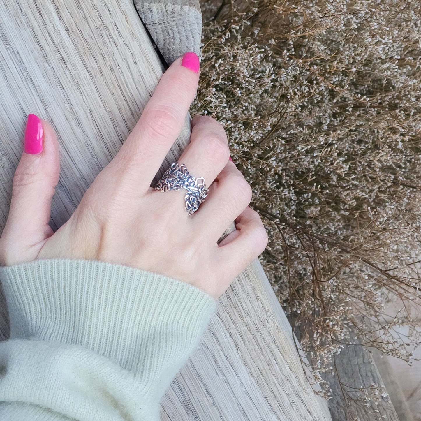 Hand wearing a solid sterling silver Mississippi River ring against a natural background