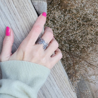 Hand wearing a solid sterling silver Mississippi River ring against a natural background