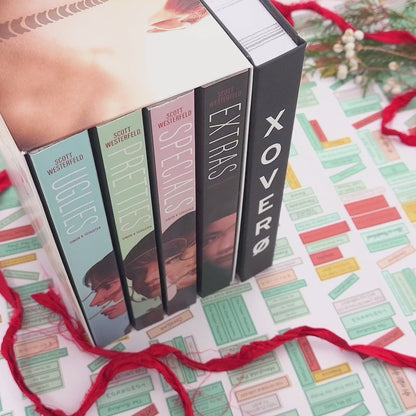 Xover0 custom Book Safe packaging, sized to match the Uglies book or series box set, opens to reveal a hidden heart-shaped compartment flocked with black suede pulp holding the Geoheart Pendant necklace in a velvet pouch.