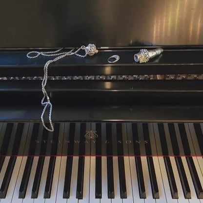 The Aṅgulimāla finger shaped sterling silver pendant necklace stores rings while you play the piano. Simply unscrew the cap, stack several rings, and replace the cap. The pendant is suspended from a long french rope chain. 