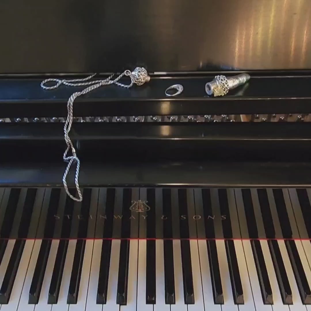 The Aṅgulimāla finger shaped sterling silver pendant necklace stores rings while you play the piano. Simply unscrew the cap, stack several rings, and replace the cap. The pendant is suspended from a long french rope chain. 