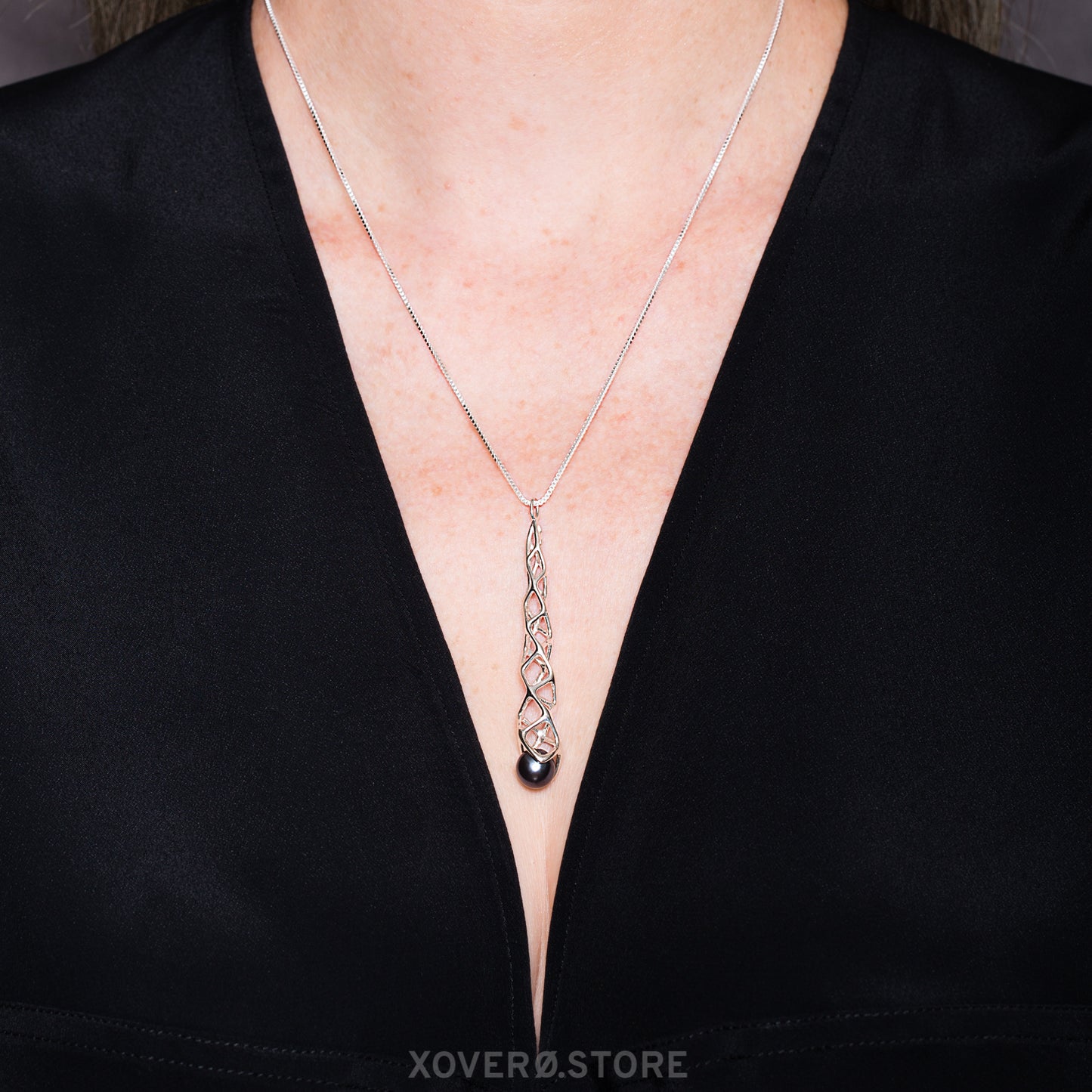 Sterling silver lattice pendant with black pearl accent on an 18 inch box chain worn with a deep V cut designer top. 