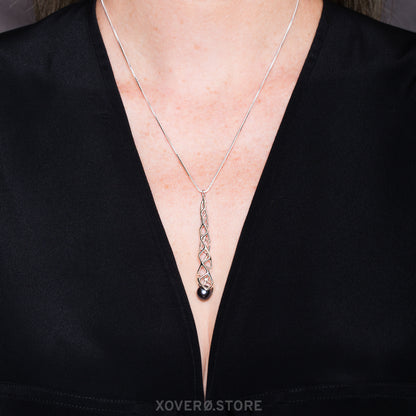 Sterling silver lattice pendant with black pearl accent on an 18 inch box chain worn with a deep V cut designer top. 