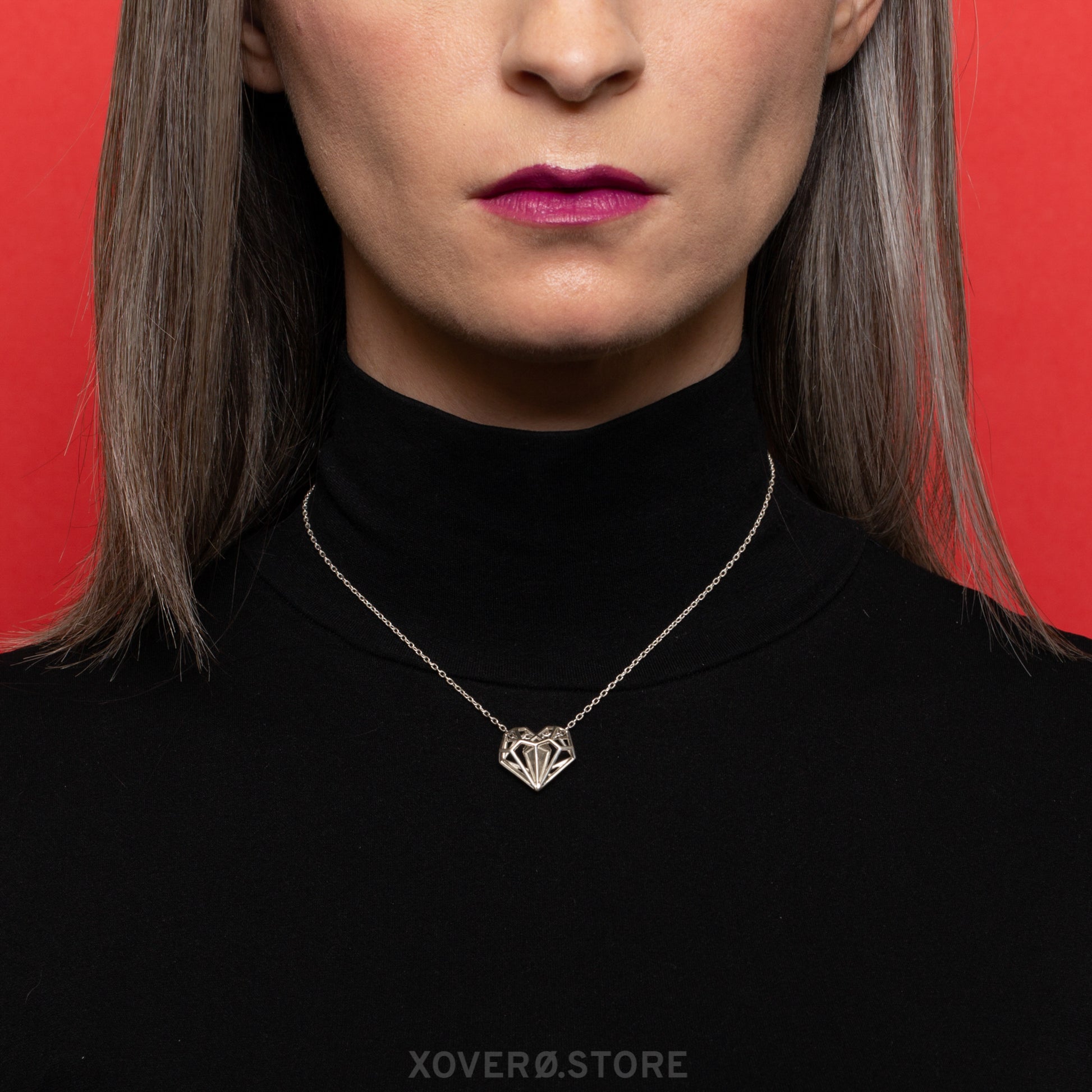 Sterling silver geometric heart pendant necklace on an adjustable chain worn at a shorter length, close to the neck in a chic choker style. Its exceptional craftsmanship and unique Art Deco-inspired latticework make it stand out. 