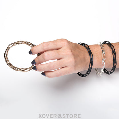 Architectural bangle bracelet made of solid sterling silver lattice structure draws attention to the wrist. 