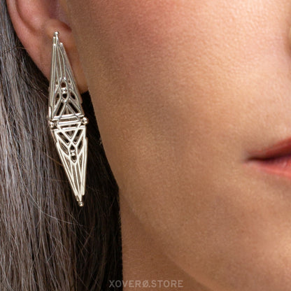 Extreme close-up of an elongated diamond-shaped sterling silver earring showing how its intricate lattice design sits on the ear.